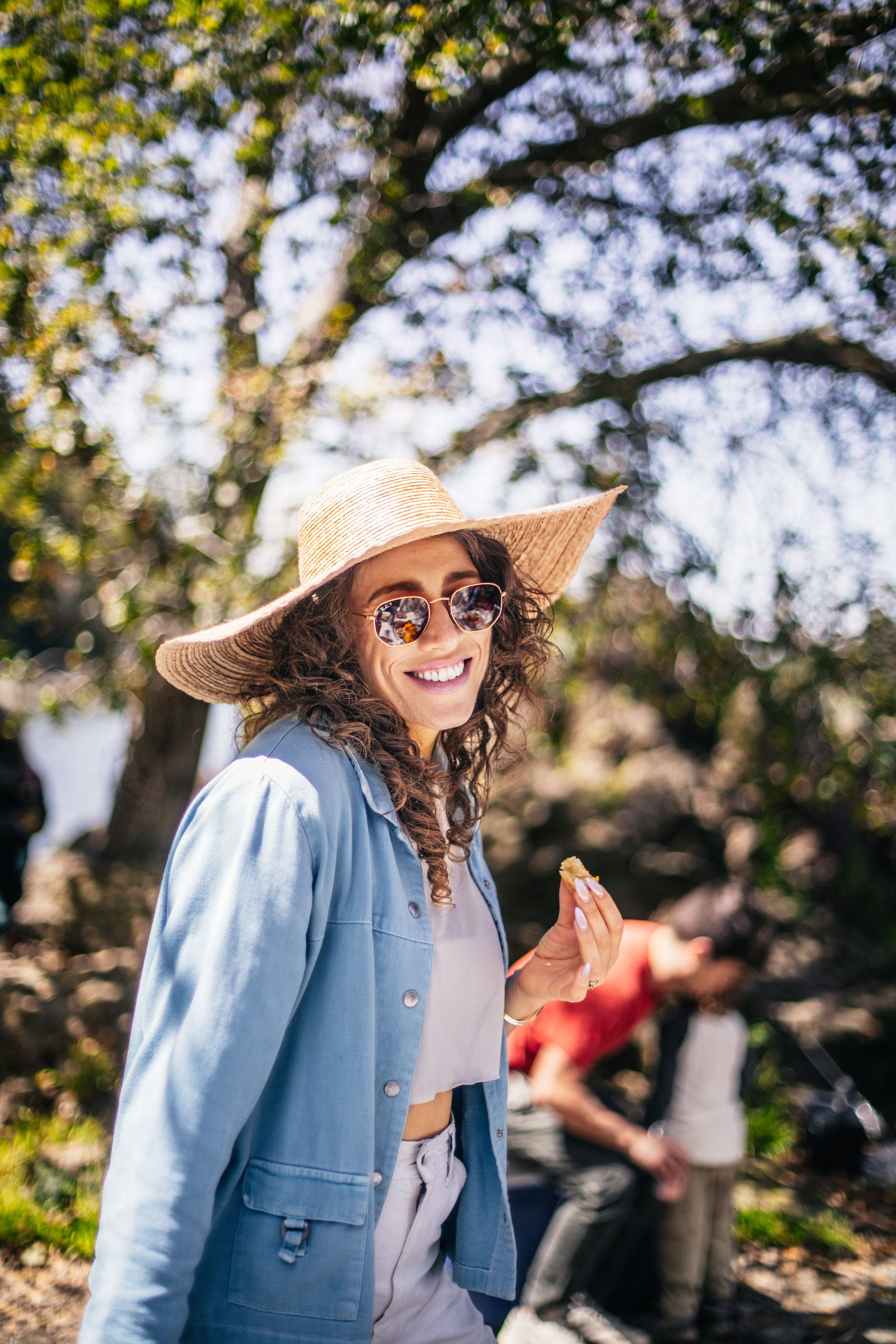 A guest in a wide-brim hat smiling at an outdoor baby shower
