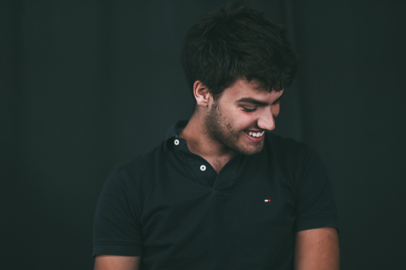 A man smiling while looking down in a quiet candid portrait