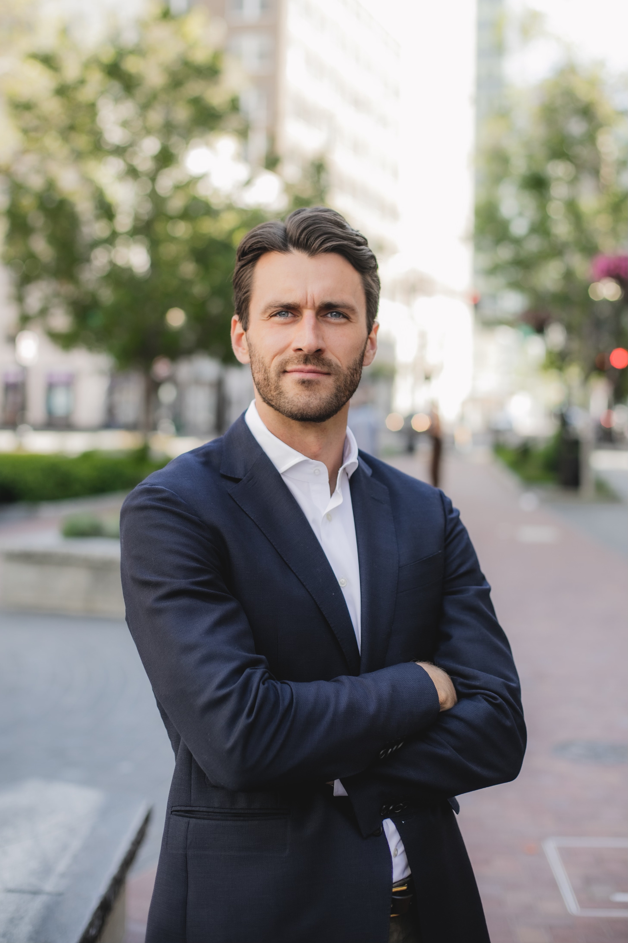 A professional portrait of a man in a dark suit on a city street