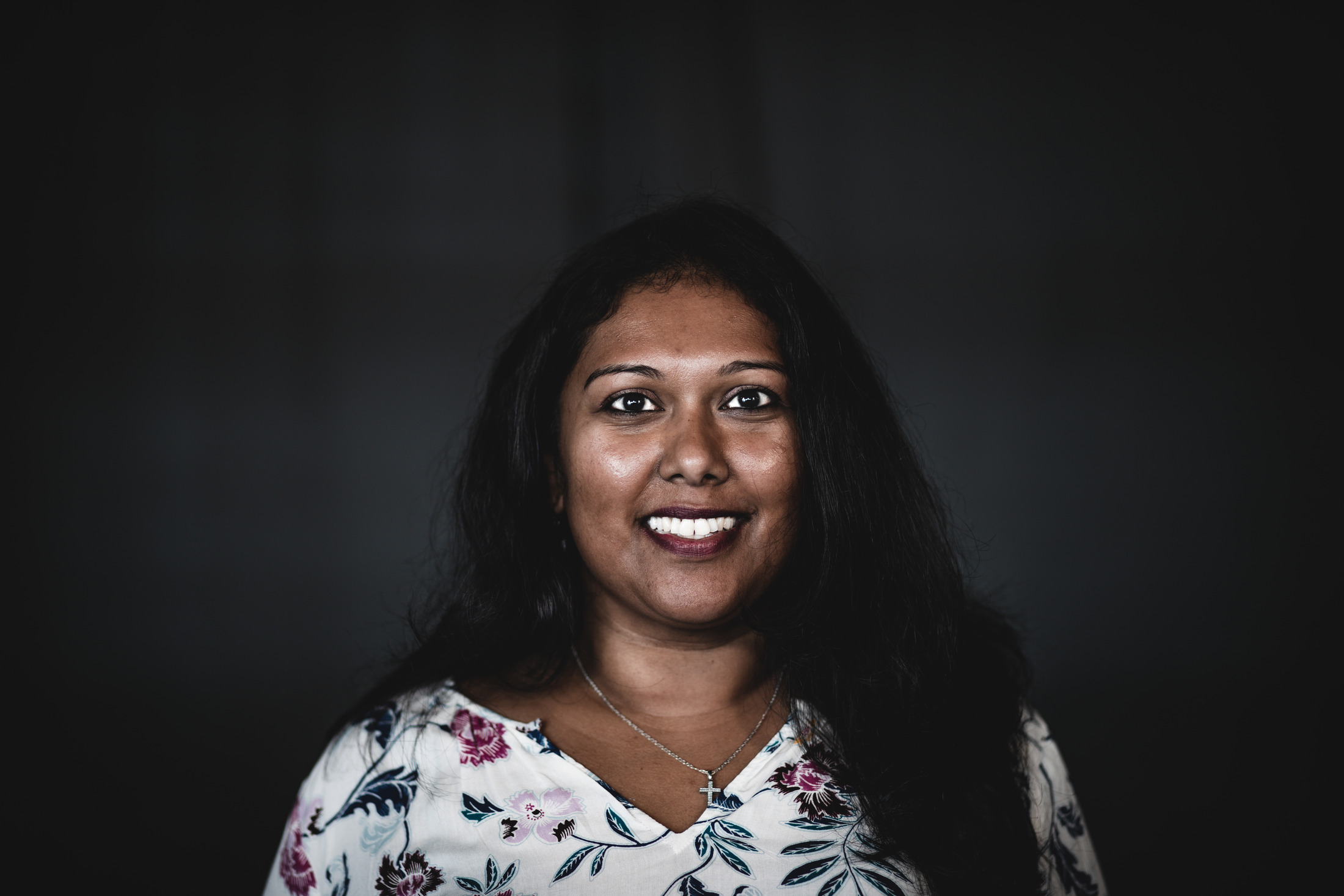 A smiling woman photographed against a dark studio background