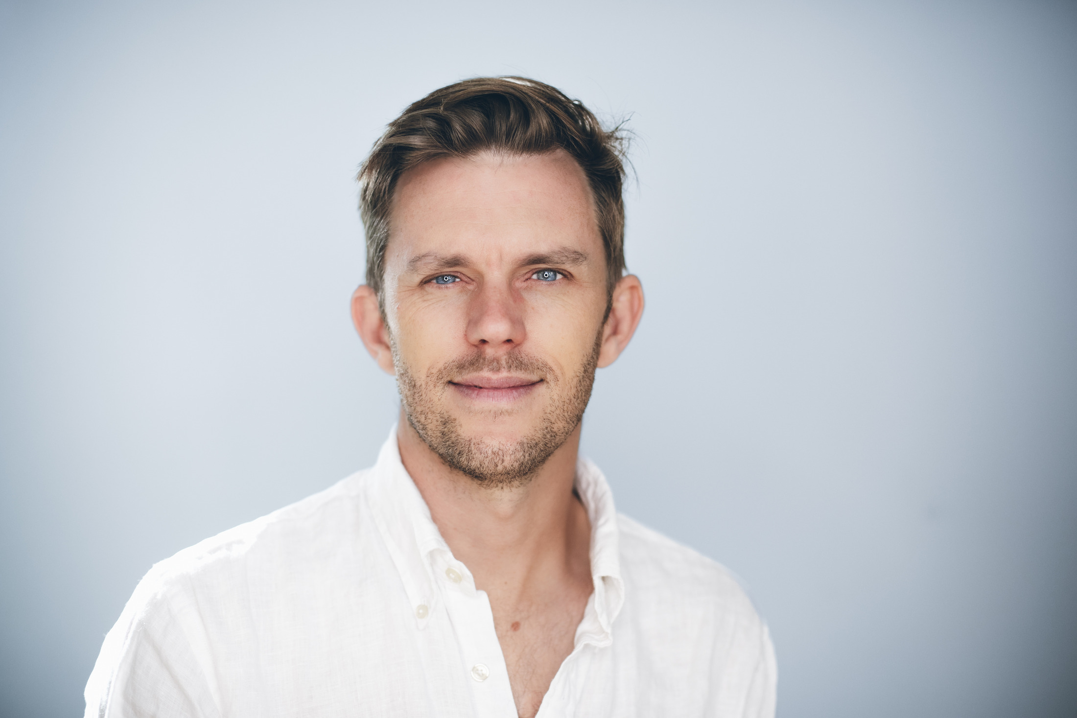 A relaxed professional headshot against a soft blue background